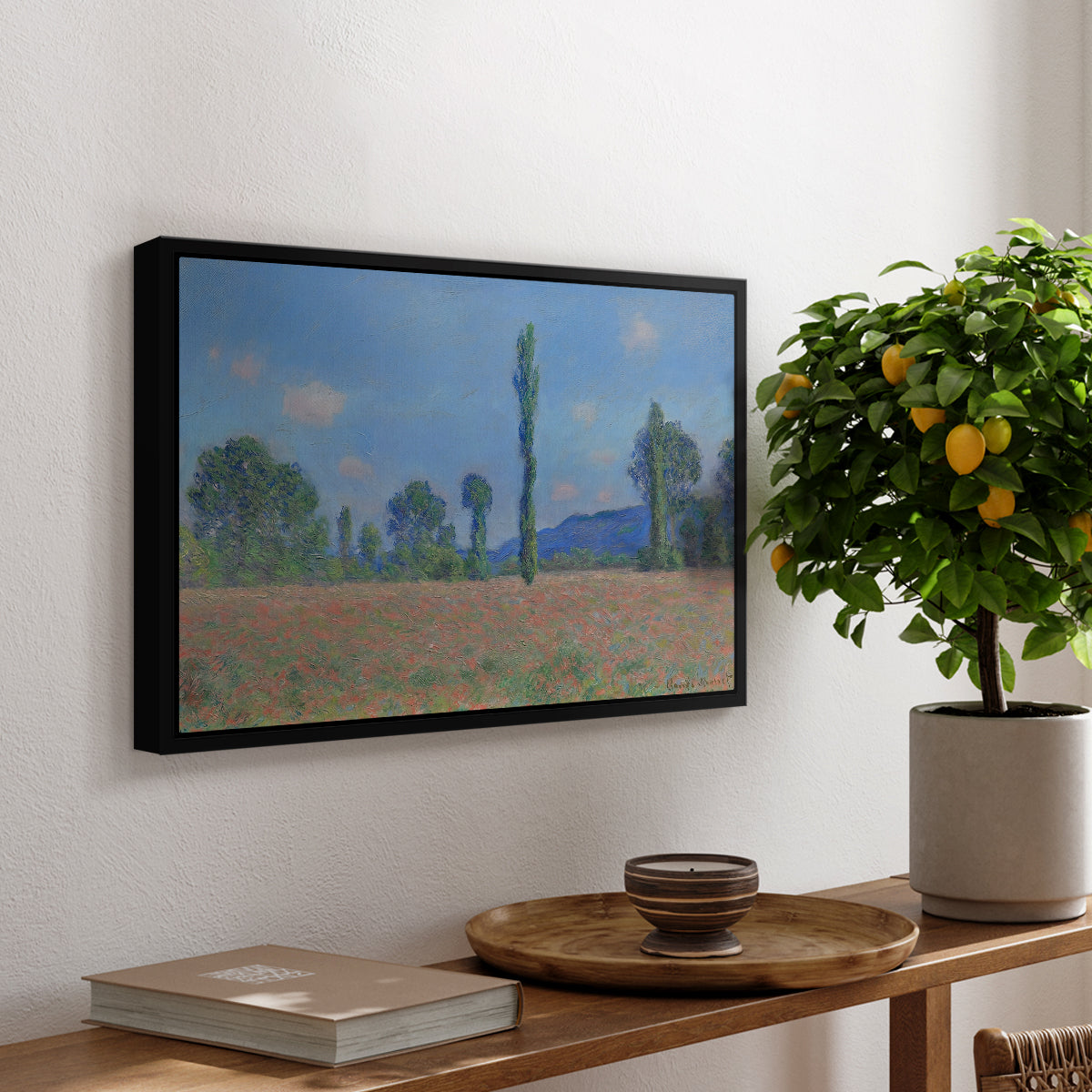 Poppy Field (Giverny), 1890-1891 by Claude Monet, presented in a black floater framed canvas featuring an expansive field of red poppies with tall trees under blue sky, displayed above a hallway console table.