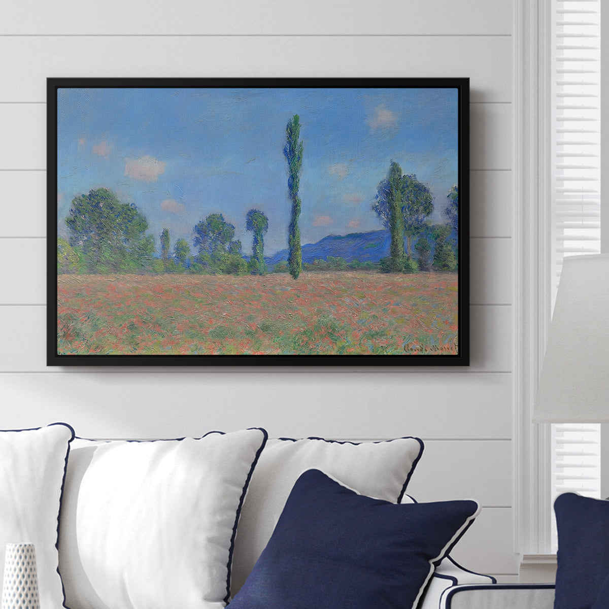 Poppy Field (Giverny), 1890-1891 by Claude Monet displayed above a sofa in a living room in a black floater frame, featuring an impressionist landscape of blooming poppies in countryside.