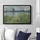 Banks of the Seine, Vétheuil, 1880 by Claude Monet displayed above a sofa in a living room in a black floater frame, featuring an impressionist view of Seine with reflections and greenery.