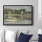 The Bridge at Argenteuil, 1874 by Claude Monet displayed above a sofa in a living room in a black floater frame, featuring an impressionist river scene with boats passing beneath bridge.