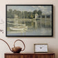 Black floater framed canvas featuring a bright landscape featuring bridge and sailboats on calm water, displayed above a cabinet in a soft-toned living room.
