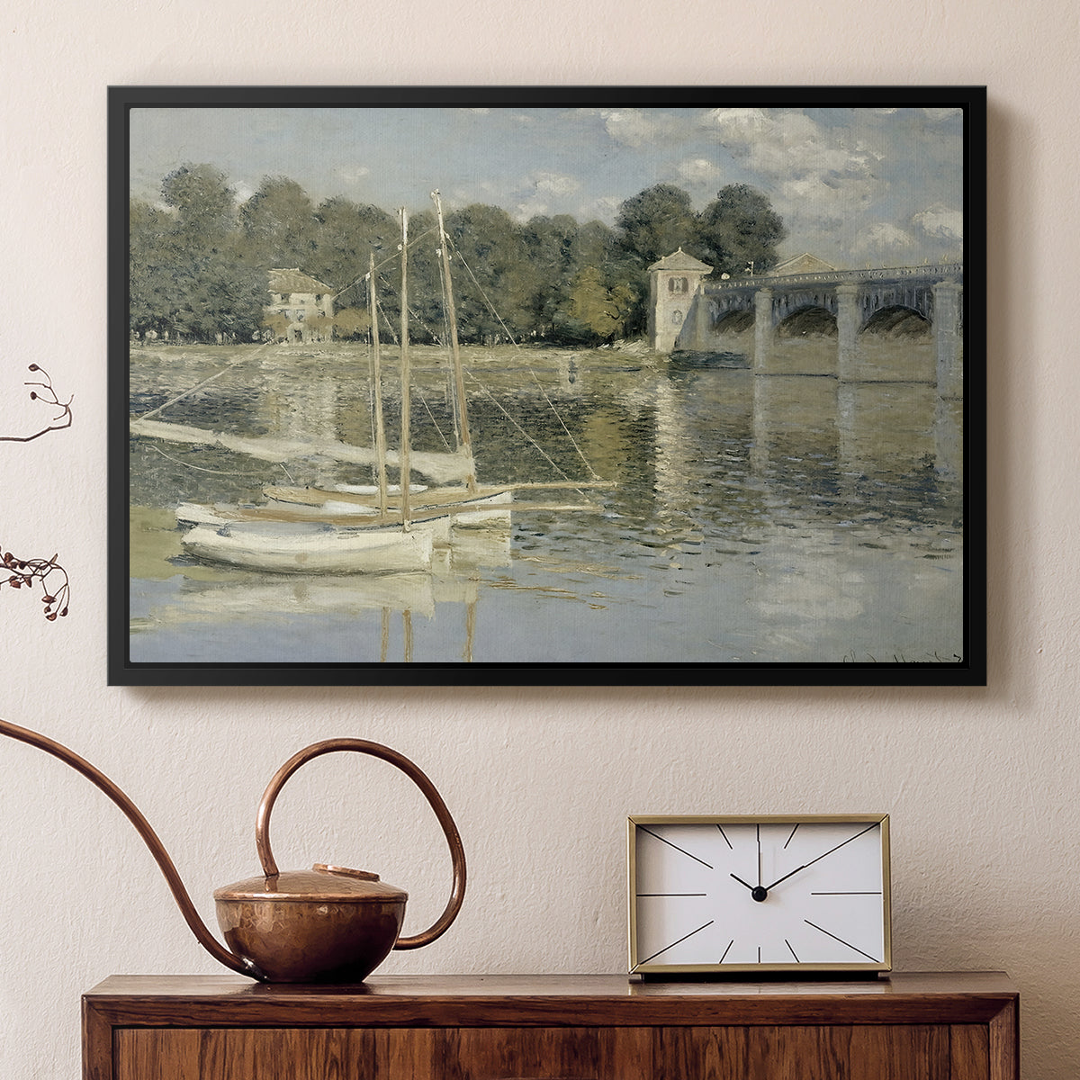 Black floater framed canvas featuring a bright landscape featuring bridge and sailboats on calm water, displayed above a cabinet in a soft-toned living room.