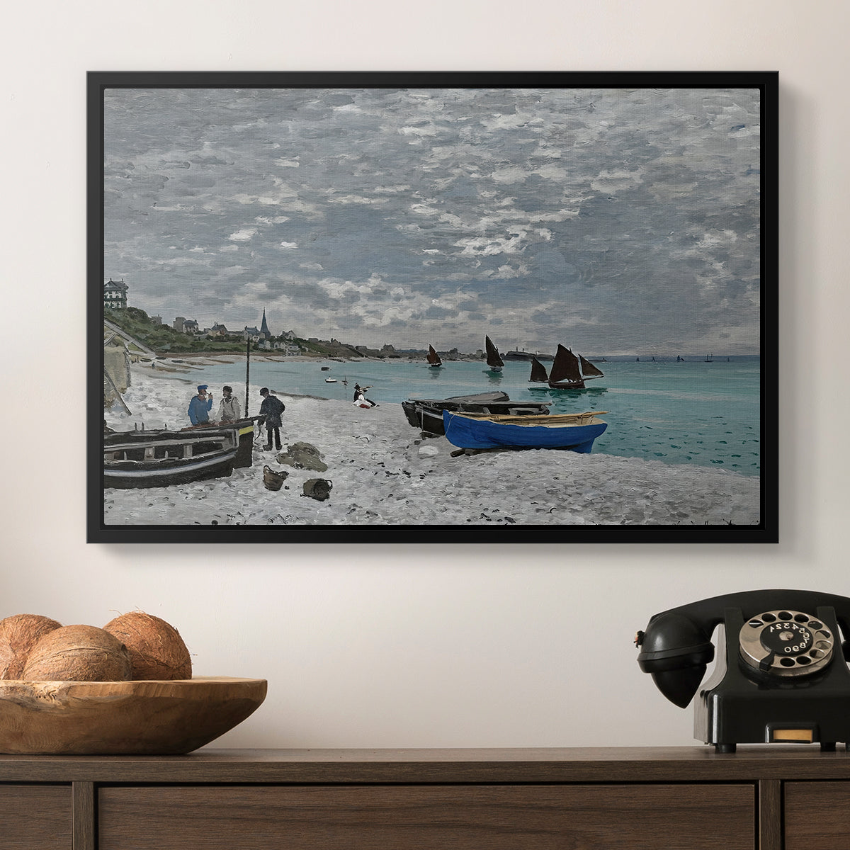 The Beach at Sainte-Adresse, 1867 by Claude Monet in a black floater framed canvas displayed above a console table in a hallway, featuring an impressionist seaside gathering with flags and ocean view.