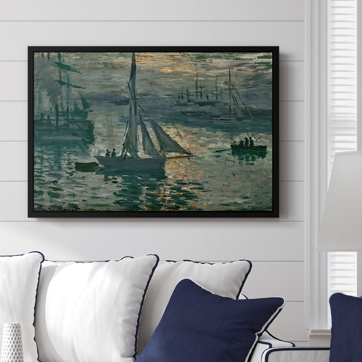 Sunrise (Marine), 1873 by Claude Monet displayed above a sofa in a living room in a black floater frame, featuring an impressionist seascape with glowing sun and misty water.