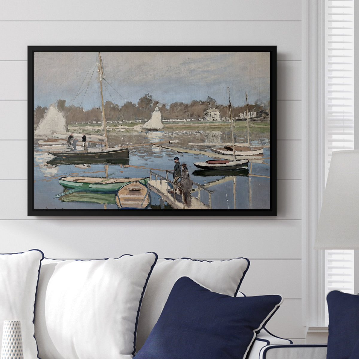 The Basin at Argenteuil, 1874 by Claude Monet displayed above a sofa in a living room in a black floater frame, featuring an impressionist boating scene with clustered masts and gentle ripples.