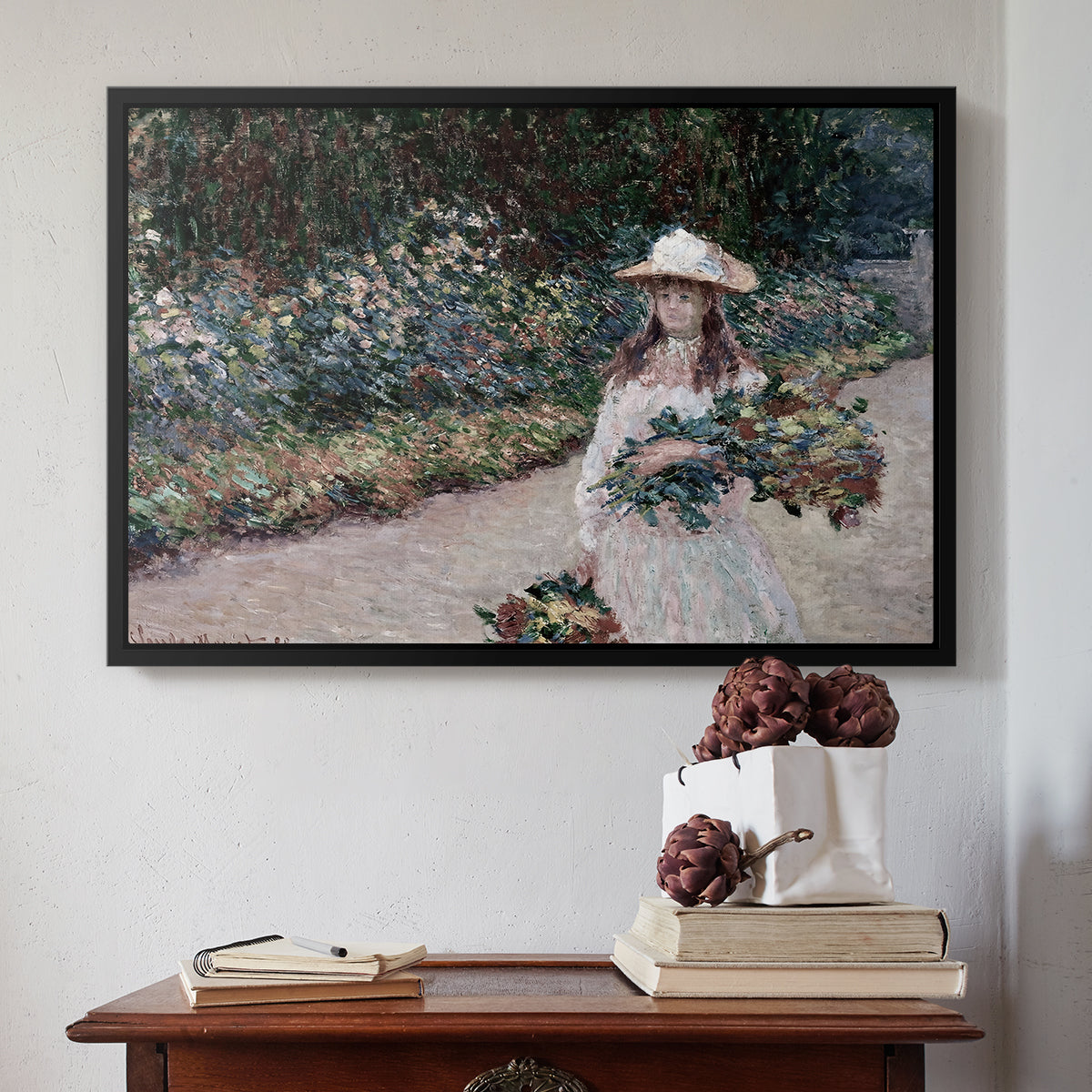 Black floater framed canvas featuring Young Girl in the Garden at Giverny, 1888 by Claude Monet above an entryway table in a minimalist foyer.
