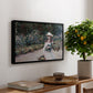 Young Girl in the Garden at Giverny, 1888 by Claude Monet, presented in a black floater framed canvas featuring a young girl seated in lush garden surrounded by blooming flowers, displayed above a hallway console table.