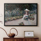 Black floater framed canvas featuring a figure resting in colorful garden under soft light, displayed above a cabinet in a soft-toned living room.