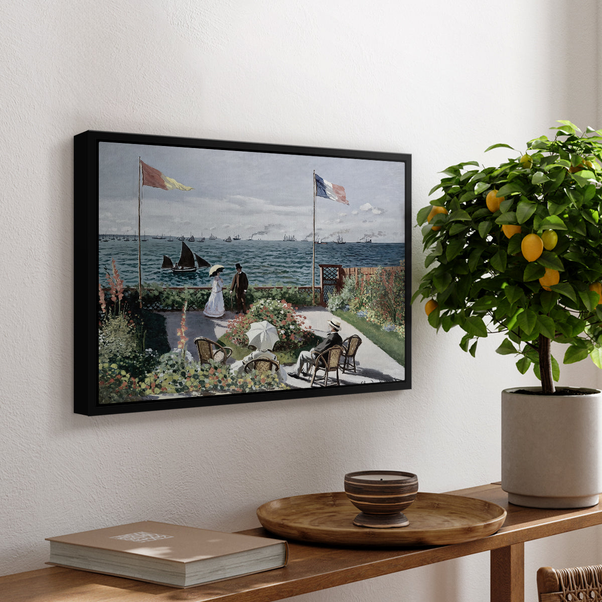 Garden at Sainte-Adresse, 1867 by Claude Monet, presented in a black floater framed canvas featuring a seaside garden with flowers, flags, and figures overlooking the water, displayed above a hallway console table.