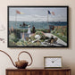 Black floater framed canvas featuring a vibrant garden scene with colorful blooms and distant sea, displayed above a cabinet in a soft-toned living room.