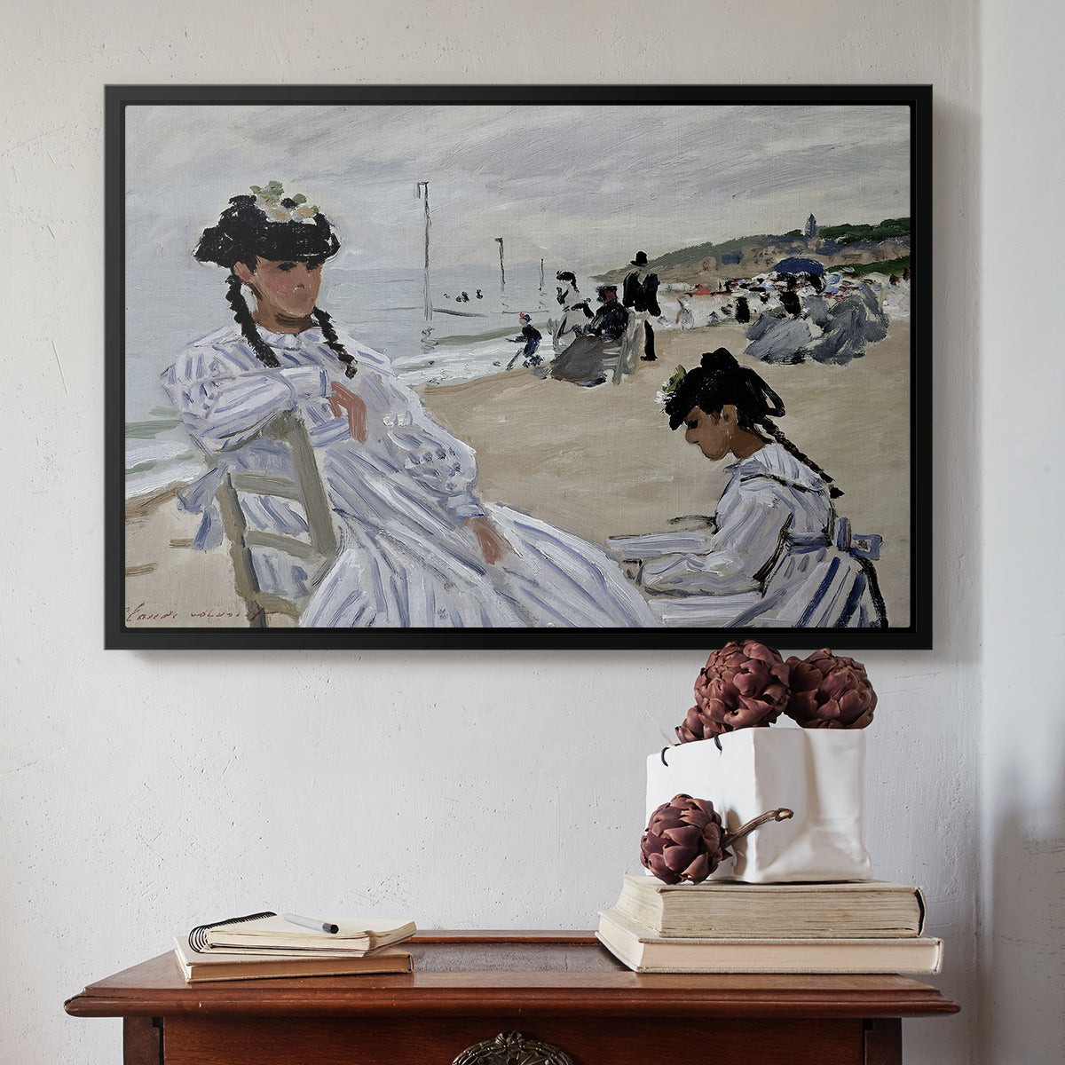Black floater framed canvas featuring On the Beach at Trouville, 1870 by Claude Monet above an entryway table in a minimalist foyer.