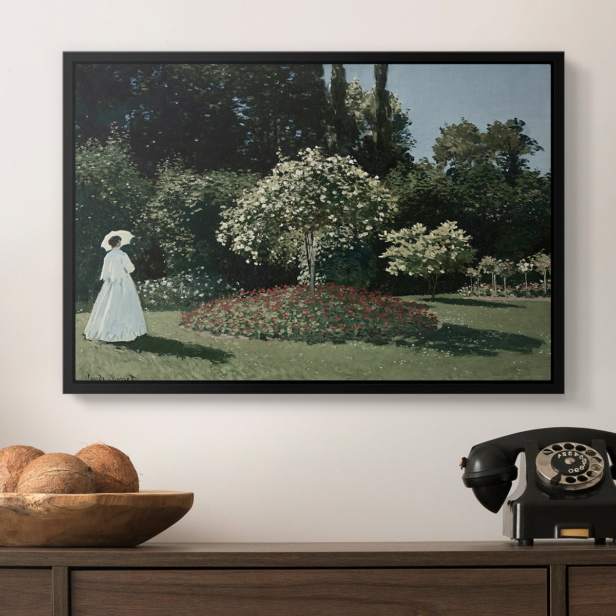 Woman in the Garden, Sainte-Adresse, 1867 by Claude Monet in a black floater framed canvas displayed above a console table in a hallway, featuring a tranquil garden portrait with soft natural light.