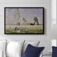 Summer (L'ete), 1874 by Claude Monet displayed above a sofa in a living room in a black floater frame, featuring an impressionist countryside scene with figure resting in shade.