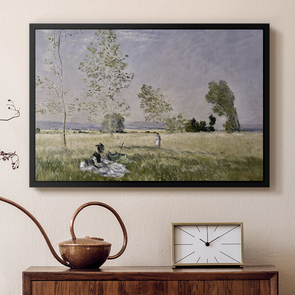 Black floater framed canvas featuring a sunlit meadow with woman surrounded by greenery, displayed above a cabinet in a soft-toned living room.