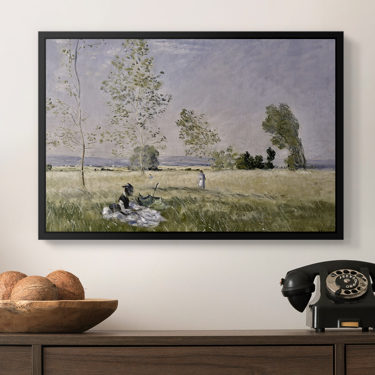 Summer (L'ete), 1874 by Claude Monet in a black floater framed canvas displayed above a console table in a hallway, featuring a tranquil summer landscape with lone figure in nature.