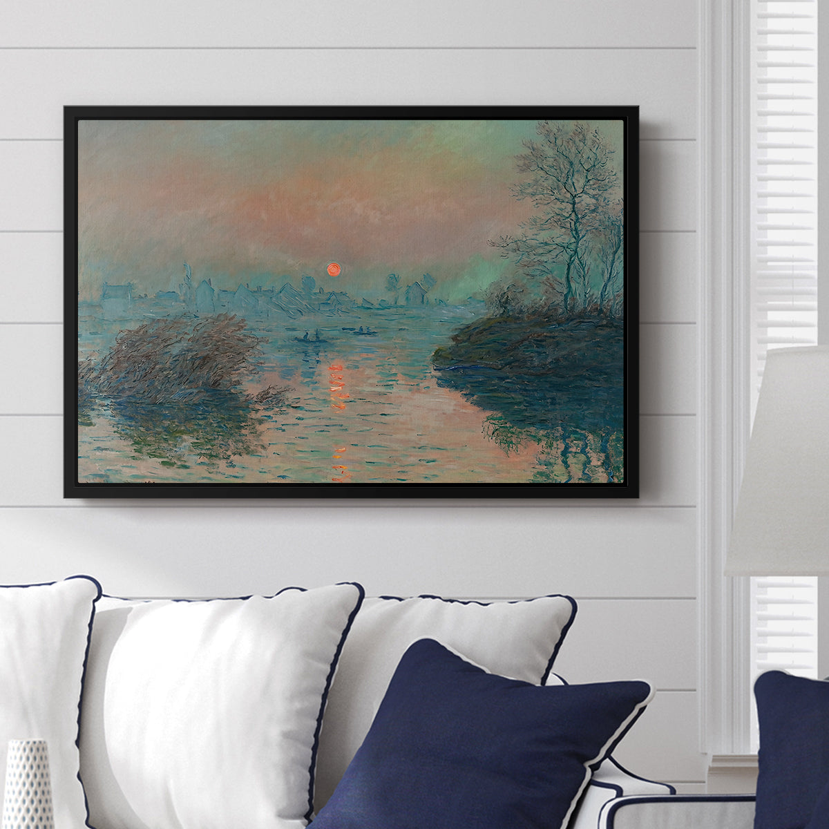 Sunset on the Seine at Lavacourt, Winter Effect, 1880 by Claude Monet displayed above a sofa in a living room in a black floater frame, featuring a winter scene with warm light reflecting on water at dusk.