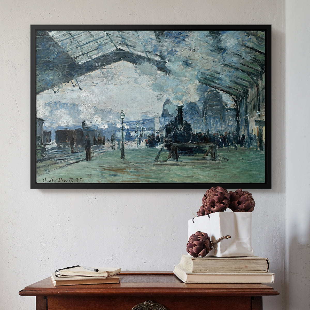 Black floater framed canvas featuring The Saint-Lazare Station, 1877 by Claude Monet above an entryway table in a minimalist foyer.