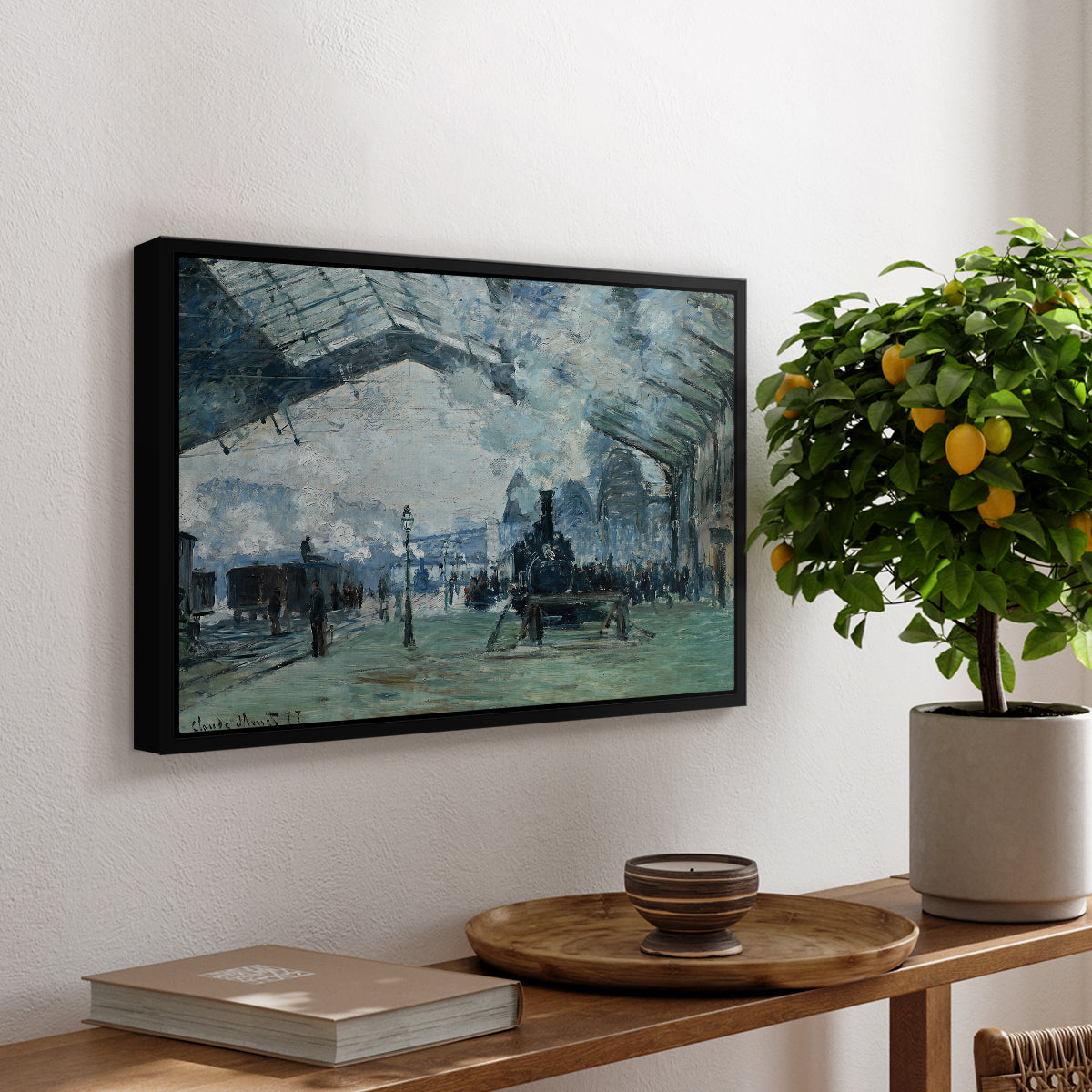 The Saint-Lazare Station, 1877 by Claude Monet, presented in a black floater framed canvas featuring trains arriving under large arched station roof with billowing steam, displayed above a hallway console table.