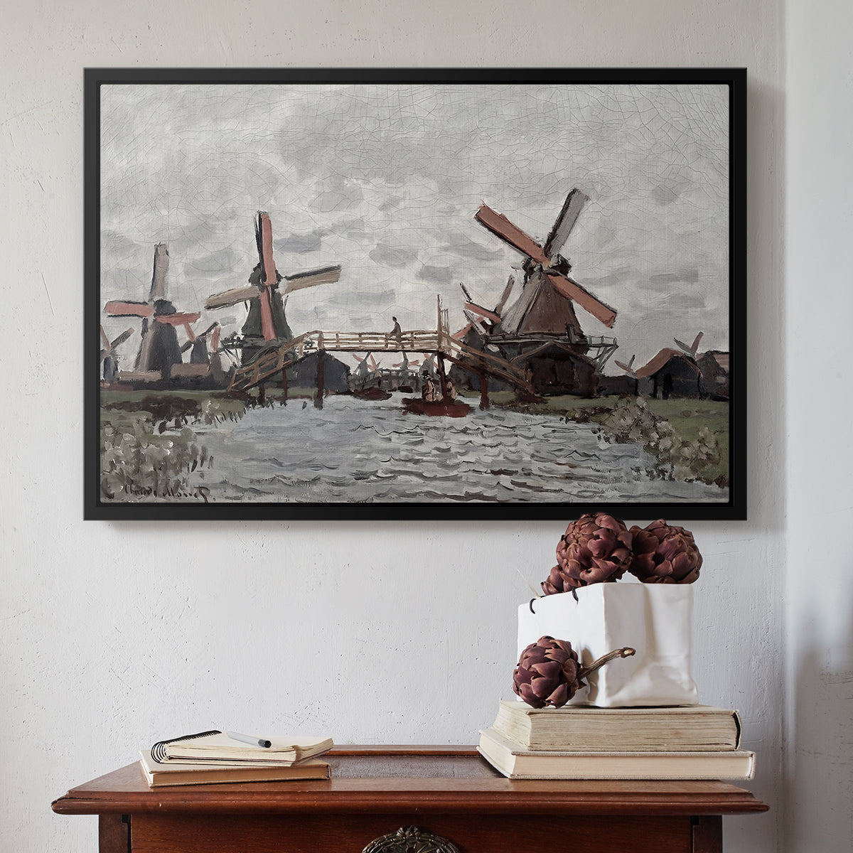 Black floater framed canvas featuring Windmills near Zaandam, 1871 by Claude Monet above an entryway table in a minimalist foyer.