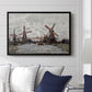 Windmills near Zaandam, 1871 by Claude Monet displayed above a sofa in a living room in a black floater frame, featuring an impressionist view of Dutch windmills along riverbank.