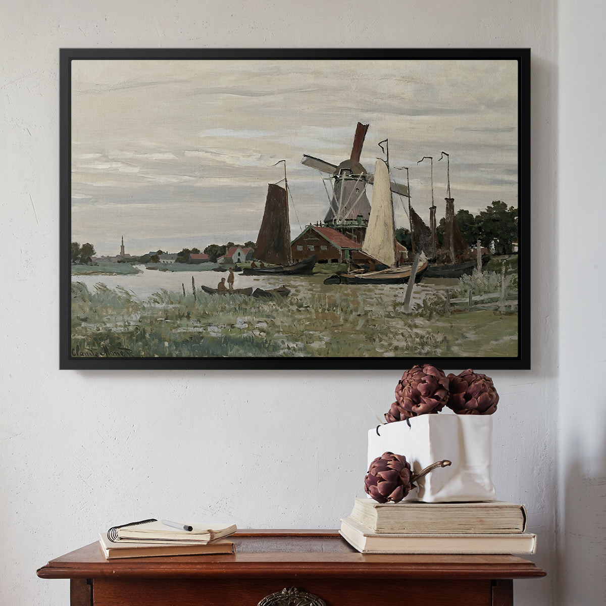 Black floater framed canvas featuring Windmill at Zaandam, 1871 by Claude Monet above an entryway table in a minimalist foyer.