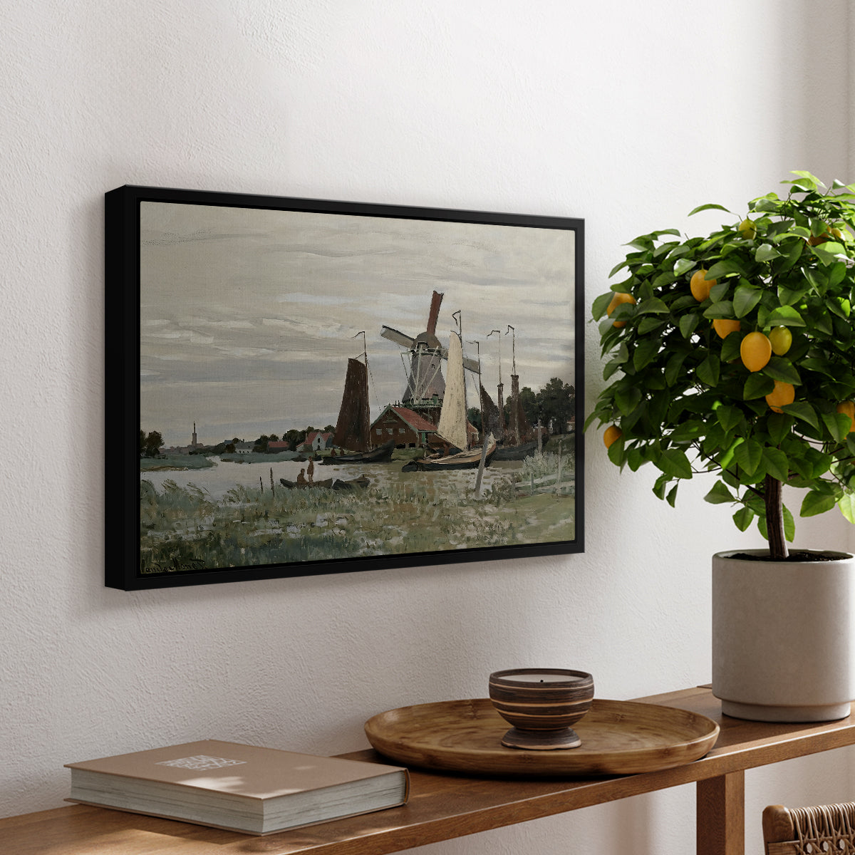 Windmill at Zaandam, 1871 by Claude Monet, presented in a black floater framed canvas featuring a single windmill beside water with surrounding buildings and sky, displayed above a hallway console table.