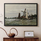 Black floater framed canvas featuring a rustic scene with windmill and reflections in water, displayed above a cabinet in a soft-toned living room.