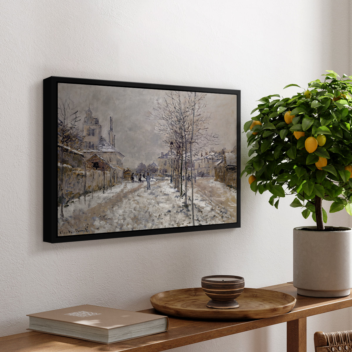 The Boulevard de Pontoise at Argenteuil, Snow Effect, 1875 by Claude Monet, presented in a black floater framed canvas featuring a snow-covered street lined with trees and buildings under winter sky, displayed above a hallway console table.