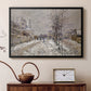 Black floater framed canvas featuring a quiet boulevard blanketed in snow with distant figures, displayed above a cabinet in a soft-toned living room.