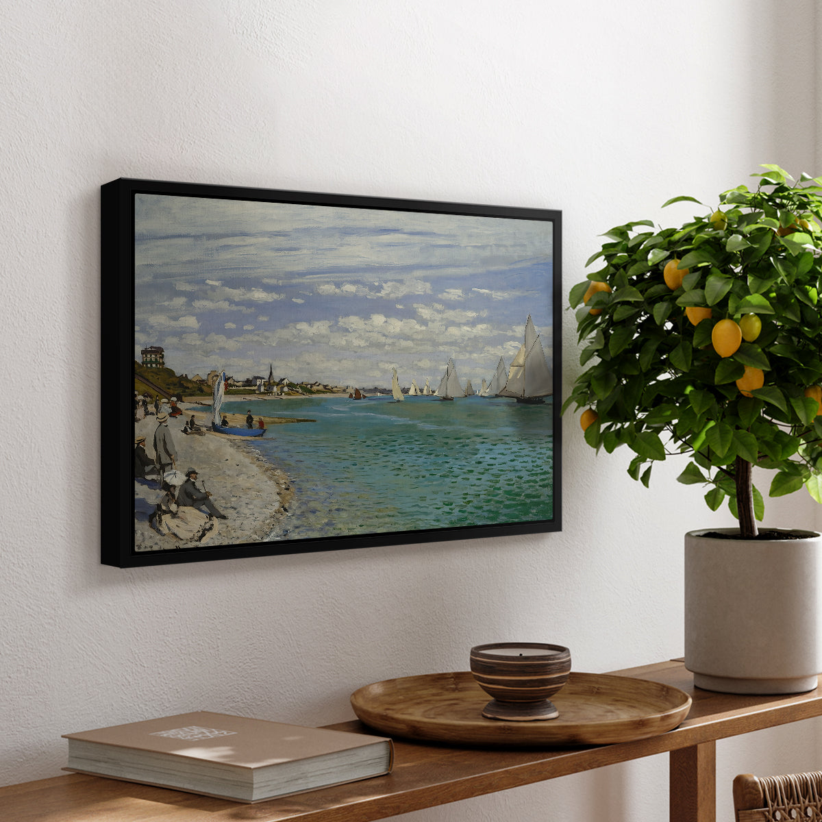 Regatta at Sainte-Adresse, 1867 by Claude Monet, presented in a black floater framed canvas featuring sailboats gathered near shore with flags and spectators along coastline, displayed above a hallway console table.