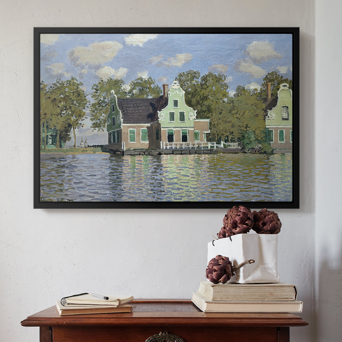 Black floater framed canvas featuring Houses on the Zaan River at Zaandam, 1871 by Claude Monet above an entryway table in a minimalist foyer.