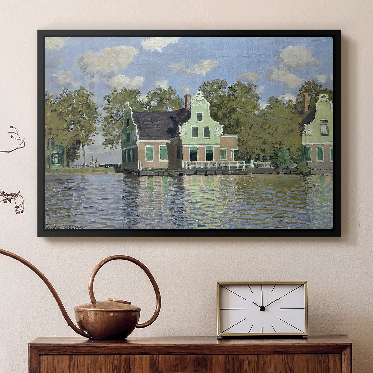 Black floater framed canvas featuring a peaceful canal scene with houses mirrored in water, displayed above a cabinet in a soft-toned living room.