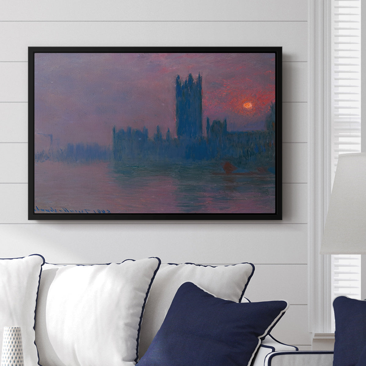 The Houses of Parliament, Sunset, 1903 by Claude Monet displayed above a sofa in a living room in a black floater frame, featuring an impressionist cityscape with warm sunset light over water.