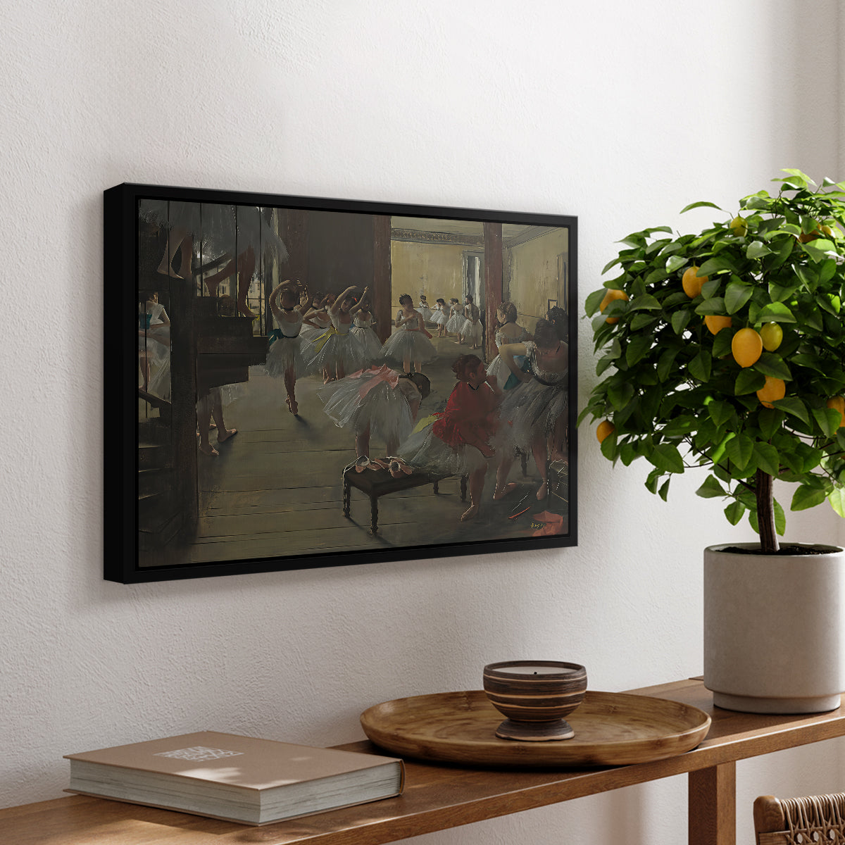 The Dance Class, c. 1873 by Edgar Degas, presented in a black floater framed canvas featuring ballerinas practicing in studio with instructor observing nearby, displayed above a hallway console table.