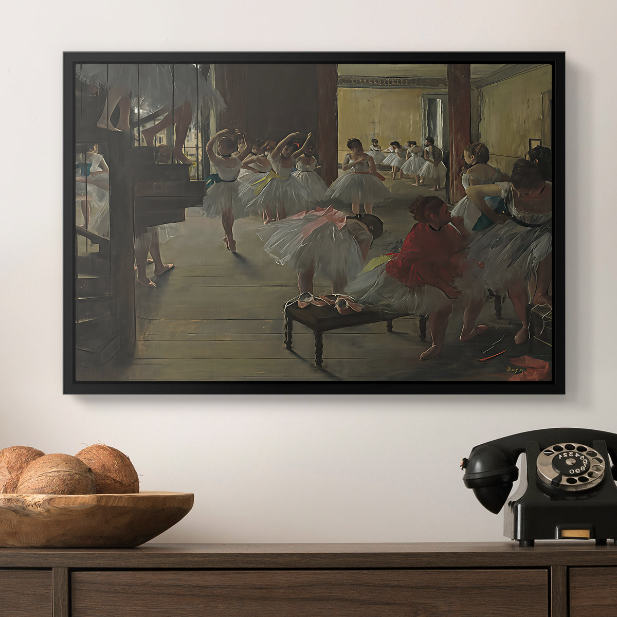 The Dance Class, c. 1873 by Edgar Degas in a black floater framed canvas displayed above a console table in a hallway, featuring a group of dancers preparing during class with natural light.