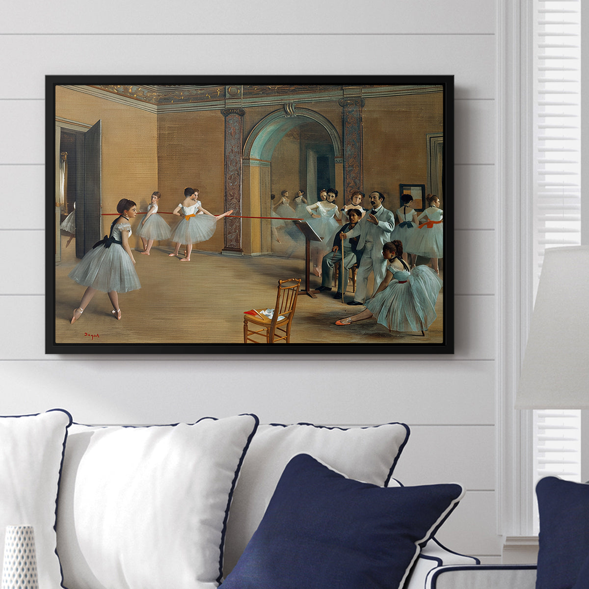 The Dance Foyer at the Opera on the Rue Le Peletier, 1872 by Edgar Degas displayed above a sofa in a living room in a black floater frame, featuring an interior scene of dancers waiting and stretching in large studio.