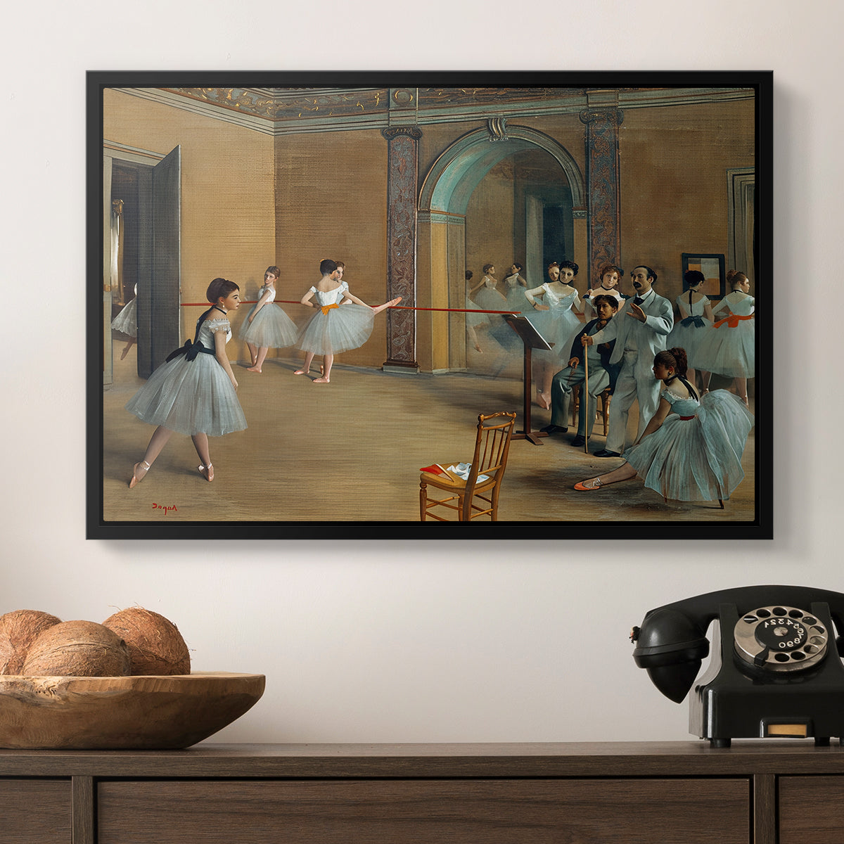 The Dance Foyer at the Opera on the Rue Le Peletier, 1872 by Edgar Degas in a black floater framed canvas displayed above a console table in a hallway, featuring an elegant rehearsal space with dancers in soft lighting.