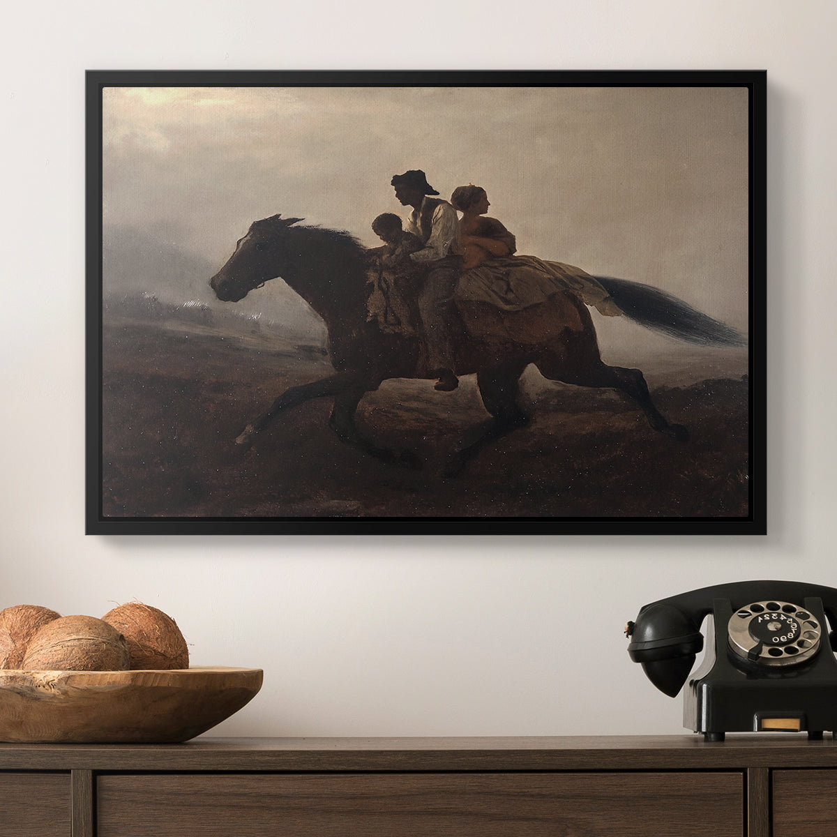 A Ride for Liberty – The Fugitive Slaves, c. 1862 by Eastman Johnson in a black floater framed canvas displayed above a console table in a hallway, featuring figures on horse moving swiftly through shadowy landscape.