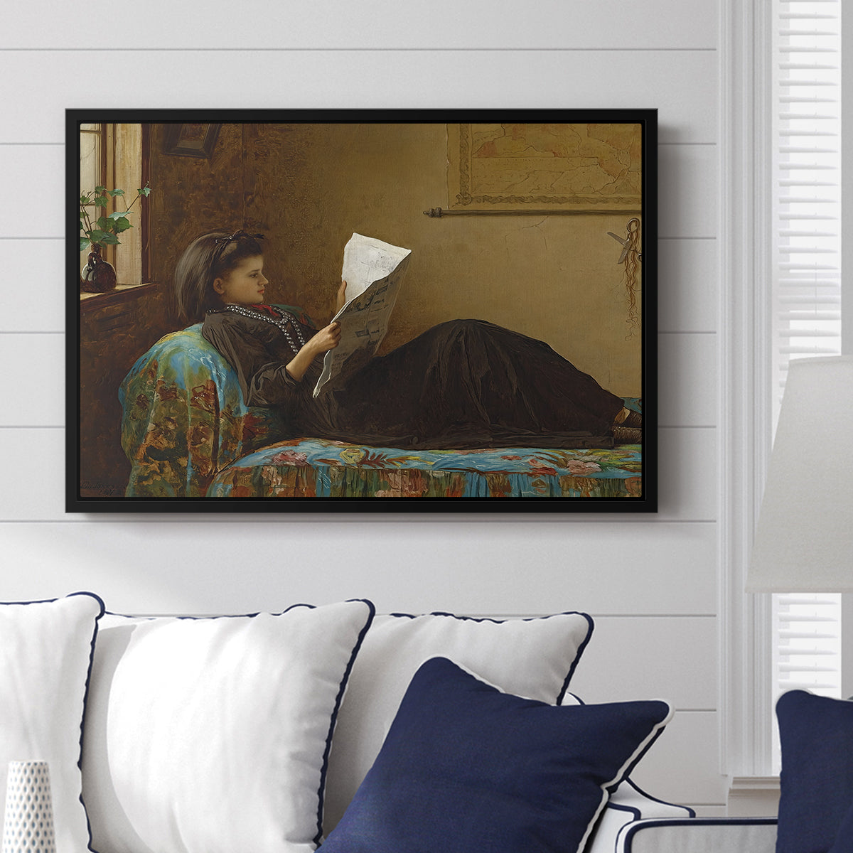 Interesting News, 1872 by Eastman Johnson displayed above a sofa in a living room in a black floater frame, featuring a domestic scene with figures reacting to shared news.