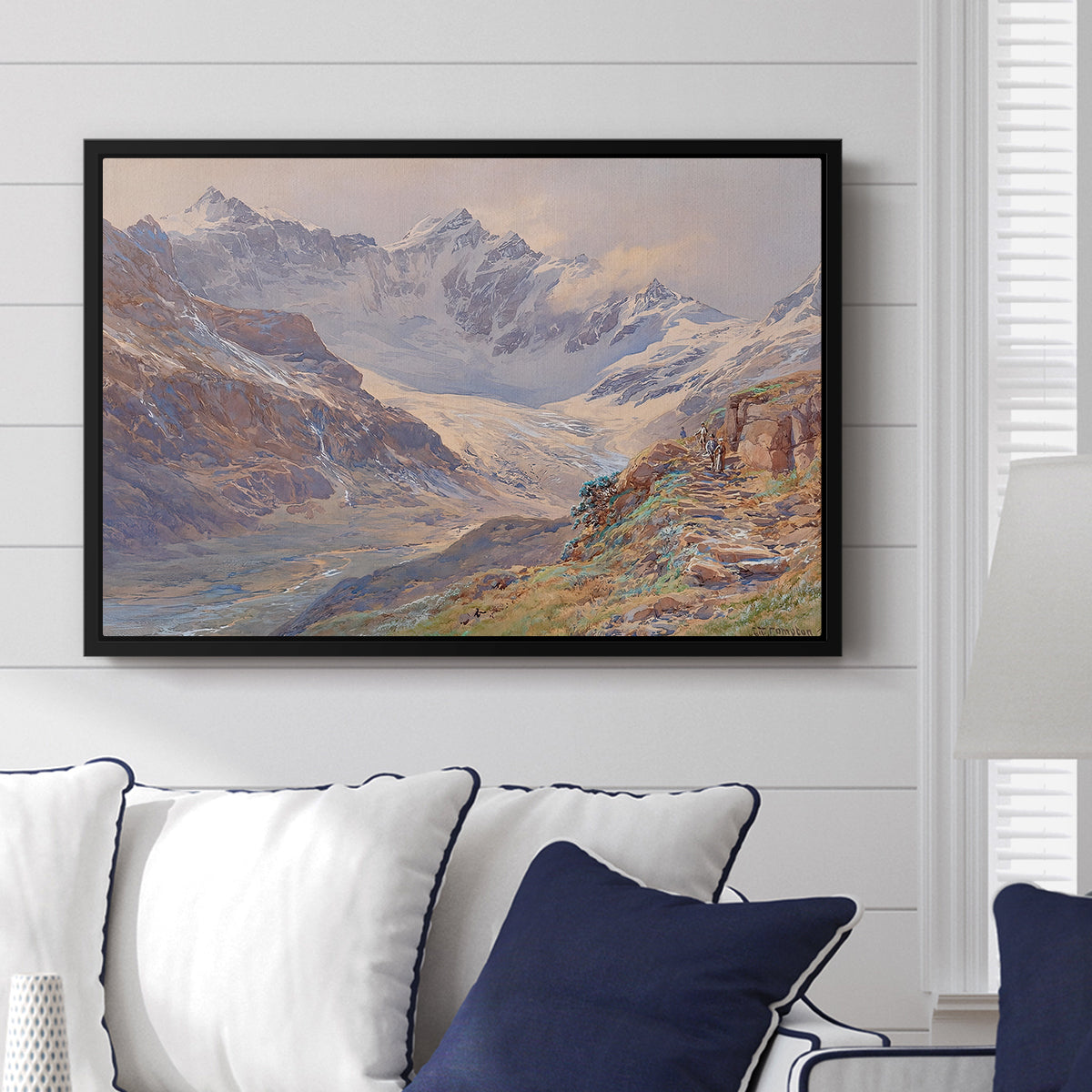 Odenwinklkees with the Johannisberg, 1902 by Edward Theodore Compton displayed above a sofa in a living room in a black floater frame, featuring a mountain scene with glacier stretching through rocky valley.