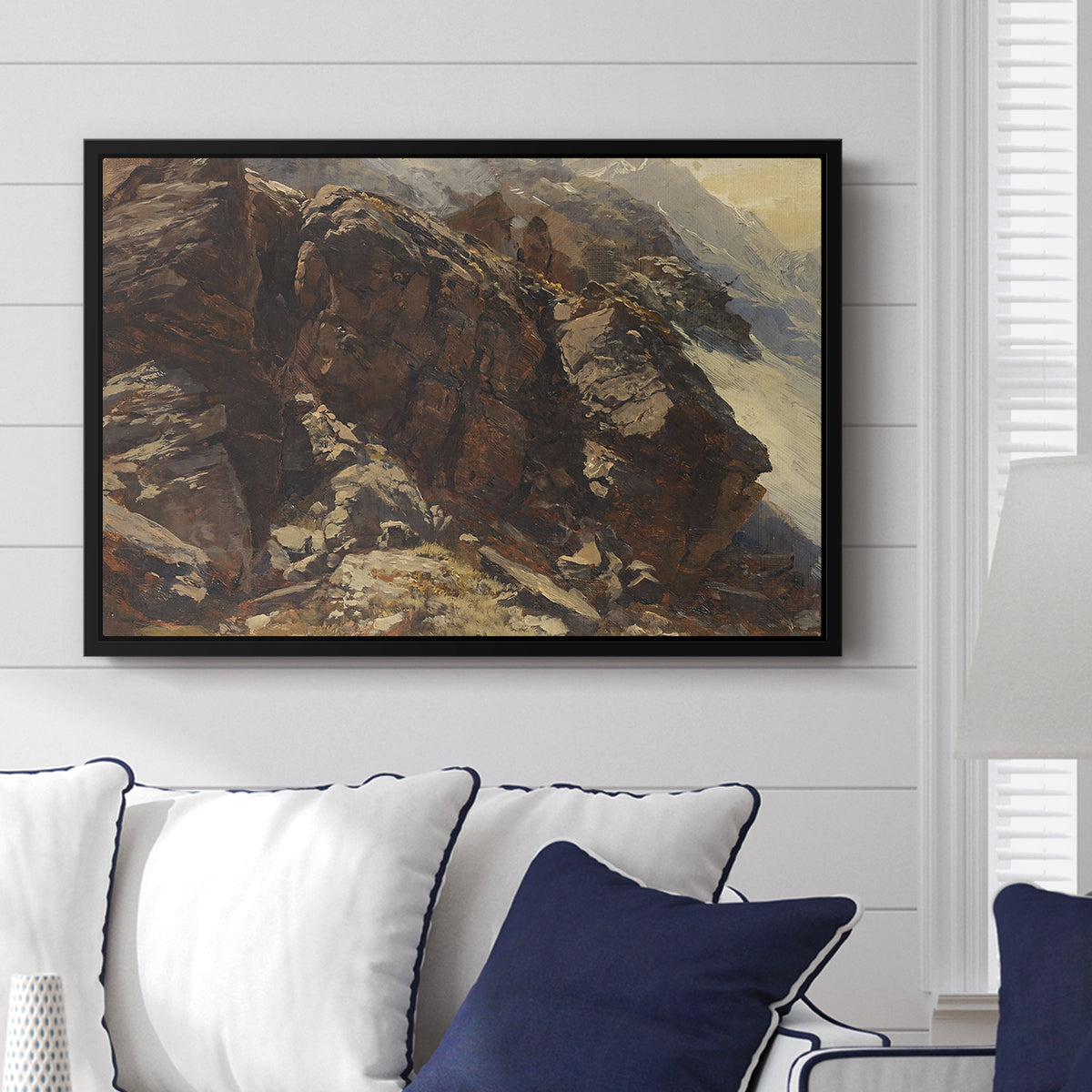 High Mountain Study, c. 1870 by Edward Theodore Compton displayed above a sofa in a living room in a black floater frame, featuring a detailed study of rugged mountain landscape with sharp contours.