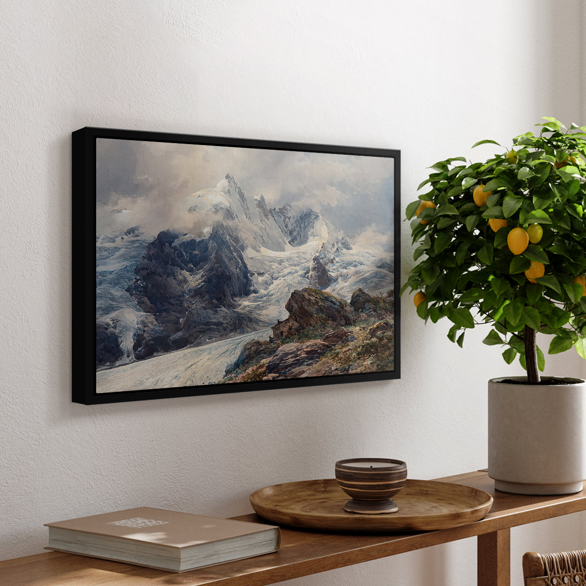 The Grossglockner, 1880 by Edward Theodore Compton, presented in a black floater framed canvas featuring a towering mountain peak rising above rocky alpine landscape, displayed above a hallway console table.