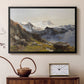 Black floater framed canvas featuring an alpine vista with towering peak and foreground terrain, displayed above a cabinet in a soft-toned living room.