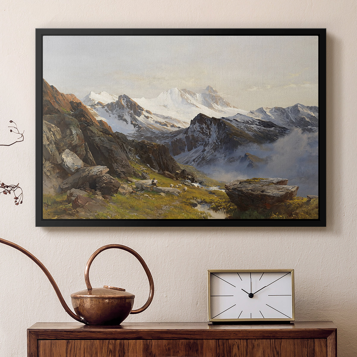 Black floater framed canvas featuring an alpine vista with towering peak and foreground terrain, displayed above a cabinet in a soft-toned living room.