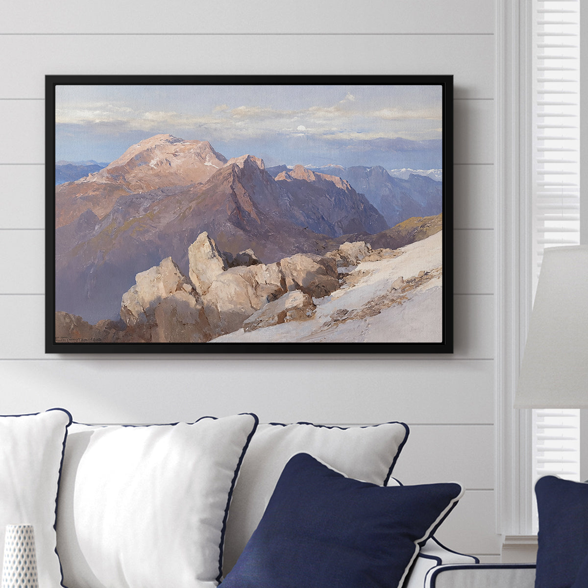 Hoher Göll from Watzmann-Hocheck, 1919 by Edward Theodore Compton displayed above a sofa in a living room in a black floater frame, featuring an alpine panorama showing layered peaks and valleys.