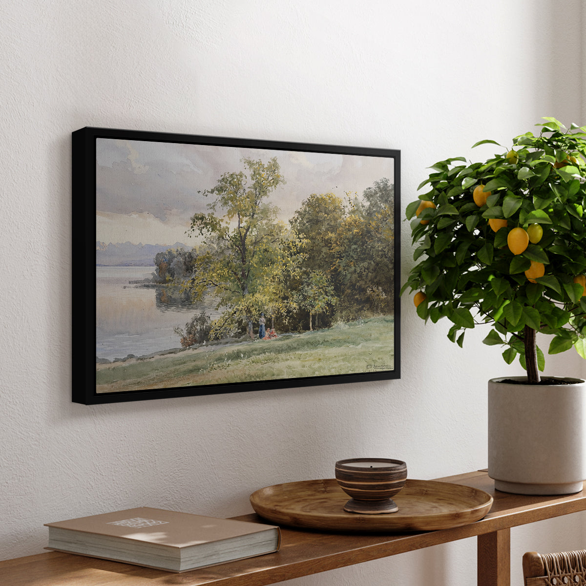 Landscape at Lake Starnberg, 1890 by Edward Theodore Compton, presented in a black floater framed canvas featuring a lakeside landscape with calm water and trees along shoreline, displayed above a hallway console table.