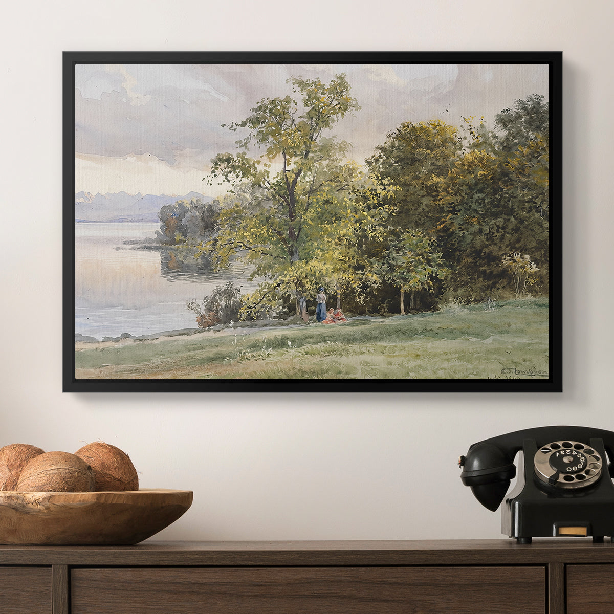 Landscape at Lake Starnberg, 1890 by Edward Theodore Compton in a black floater framed canvas displayed above a console table in a hallway, featuring a tranquil lakeside view with soft atmospheric tones.