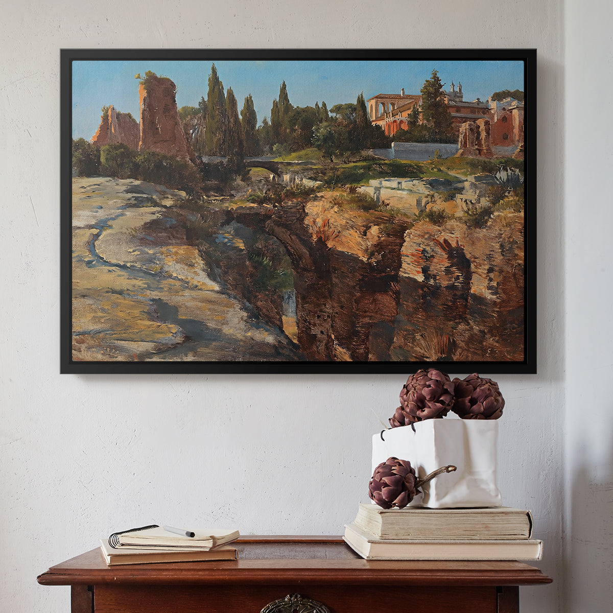 Black floater framed canvas featuring Palatine in Rome, c. 1921 by Edward Theodore Compton above an entryway table in a minimalist foyer.