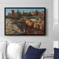 Palatine in Rome, c. 1921 by Edward Theodore Compton displayed above a sofa in a living room in a black floater frame, featuring an architectural scene of ancient structures in sunlit environment.