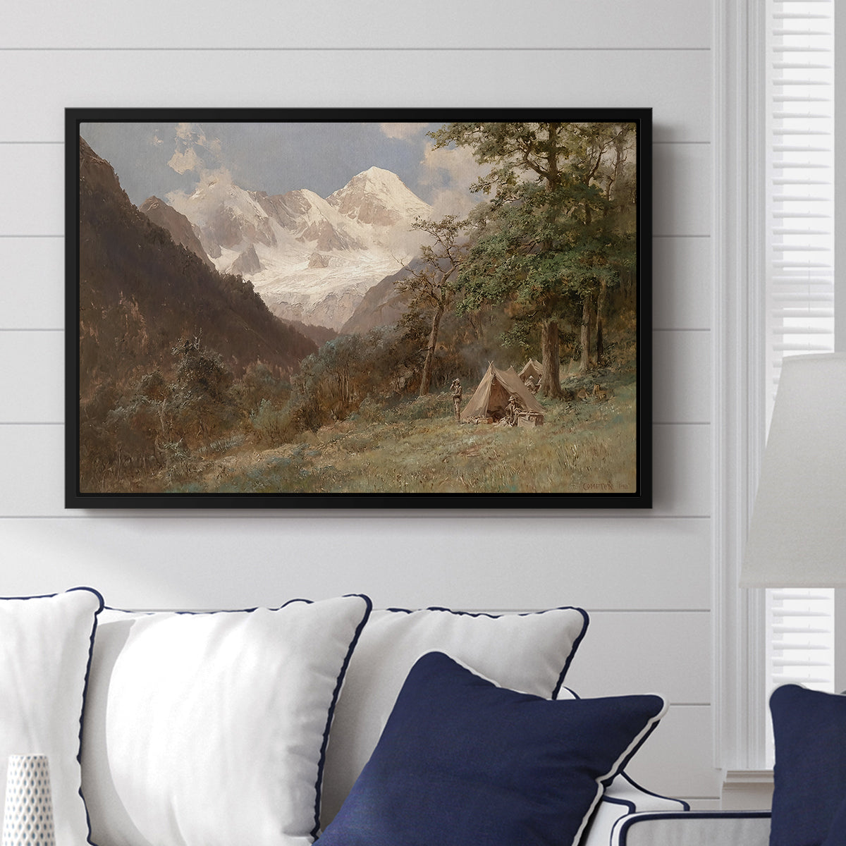 Landscape in the Caucasus, c. 1921 by Edward Theodore Compton displayed above a sofa in a living room in a black floater frame, featuring an expansive view of Caucasus mountains under open sky.